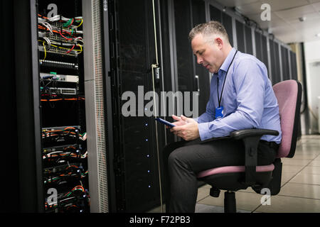 Technician using laptop in server room Stock Photo