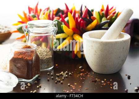 Fresh colorful chili peppers and ground chili pepper with mortar and pestle. Stock Photo