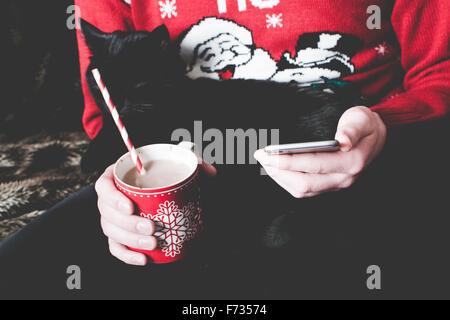 Man wearing a Christmas jumper and using his smartphone Stock Photo