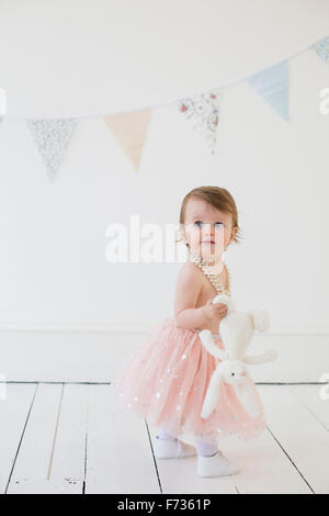 Young girl holding a cuddly toy, standing in a photographers studio, posing for a picture. Stock Photo