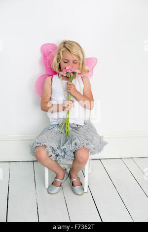 Young girl posing for a picture in a photographers studio, holding a bunch of flowers. Stock Photo