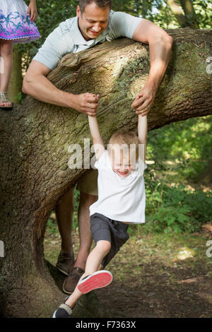 Father playing with his son by a tree in a forest. Stock Photo