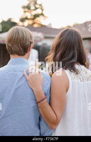 Rear view of a couple standing side by side in a garden, woman touching man's shoulder. Stock Photo