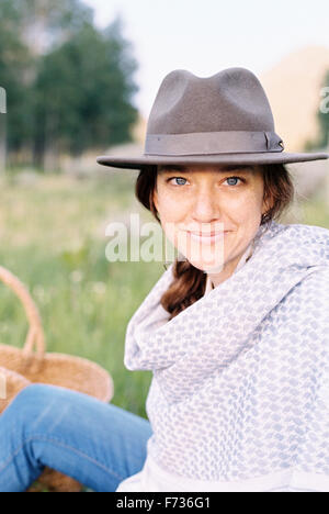 A woman in a hat and woollen shawl sitting in a meadow. Stock Photo