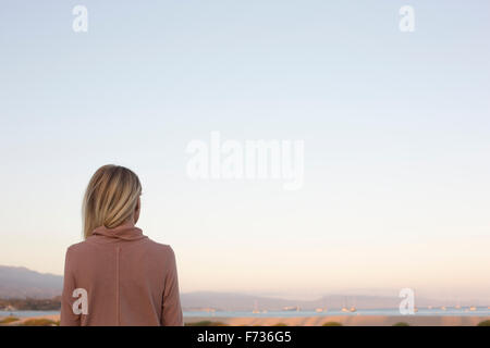 Blond woman standing at the ocean. Stock Photo