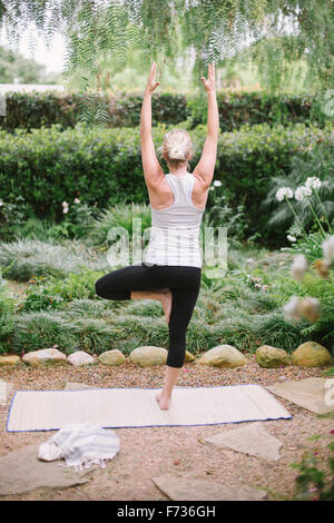 Blond woman doing yoga in a garden. Stock Photo