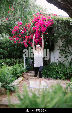 Blond woman doing yoga in a garden. Stock Photo