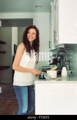 Woman standing in a kitchen preparing a pot of tea. Stock Photo