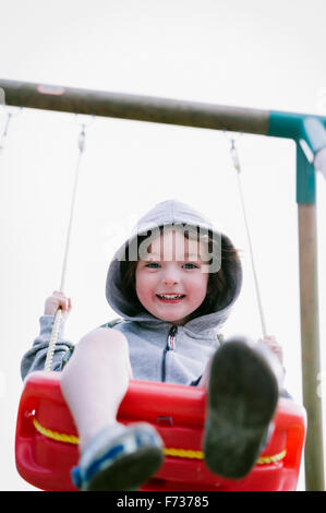 A boy in a hooded fleece, sitting on a swing Stock Photo