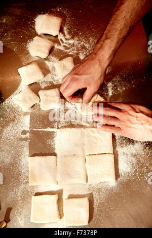 A baker working on a floured surface, dividing the prepared dough into squares. Stock Photo