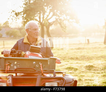 A farmer sitting on a quad bike in a field surveying his land. Stock Photo