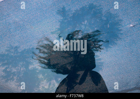 Double exposure of a young man twirling and tossing his hair with silhouette of a tree behind jute fabric Stock Photo