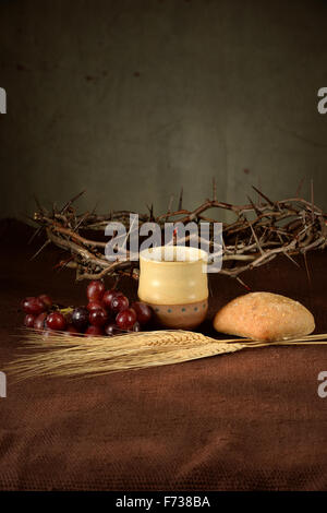 Table with cup of wine, bread, grapes, wheat, and crown of thorns Stock Photo