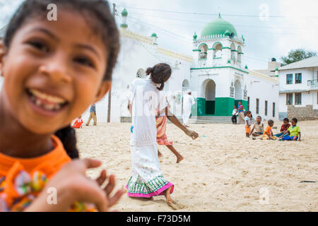 LAMU, KENYA, AFRICA. Young girls dance and play in a sand courtyard of a white mosque. Stock Photo