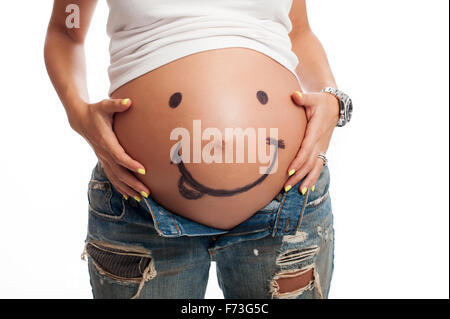 A smiley face drawn on a woman's pregnant belly. Stock Photo