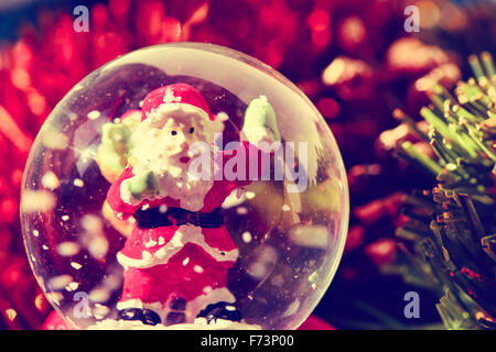 closeup of a christmas snow globe with a santa claus in it and some other christmas ornaments Stock Photo