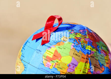 closeup a world globe with a red ribbon for the fight against AIDS Stock Photo
