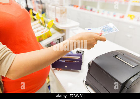 pregnant woman with money at cashbox in drugstore Stock Photo