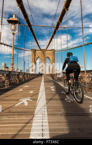 Cyclist riding her bike on Brooklyn Bridge, New York, USA