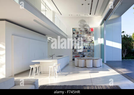 Open plan dining and kitchen area with bookshelves in modern white house, Israel, Middle East Stock Photo