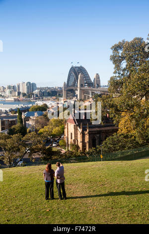Couple looking out over the Rocks district from Observatory Park to Walsh Bay and Sydney Harbour Bridge Sydney NSW Australia Stock Photo