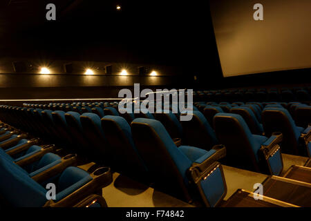 Seats and the screen in a movie theater or cinema with lights dimmed and nobody Stock Photo