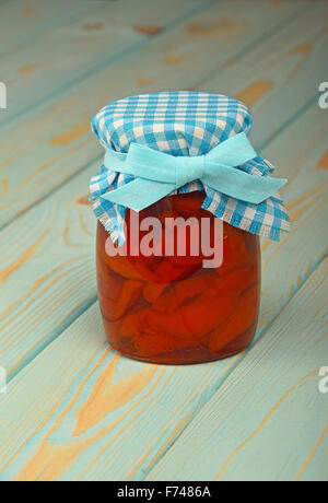 One glass jar of homemade quince jam with textile top decoration at blue painted vintage wooden surface Stock Photo