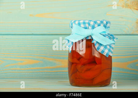 One glass jar of homemade quince jam with textile top decoration at blue painted vintage wooden surface Stock Photo