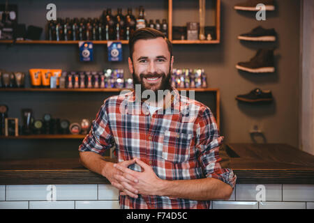 Joyful smiling content  bearded man in checkered shirt posing in barbershop Stock Photo