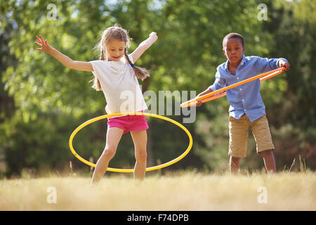Girl and boy with hula hoop playing at the park Stock Photo