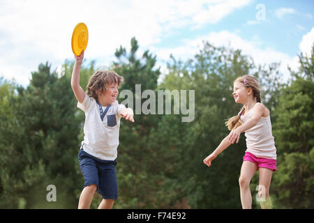 Happy boy and girl playing with a frisbee in summer Stock Photo