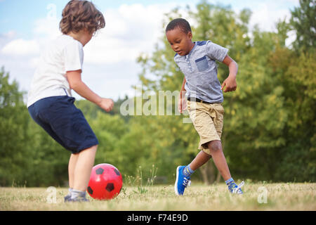 Two kids playing soccer in summer Stock Photo