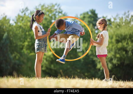 Boy jumps through hula hoop at the park Stock Photo