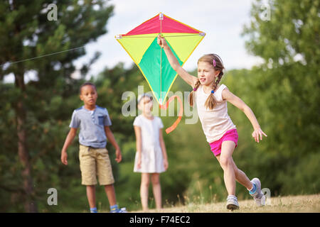 Group of kids flying a kite in summer in the nature Stock Photo