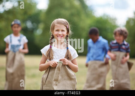 Happy girl with braided hair at sack race smiling Stock Photo
