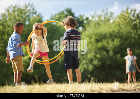 Girl jumps thourgh hula hoop at the park Stock Photo