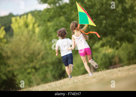 Boy and girl having fun flying a kite in summer Stock Photo