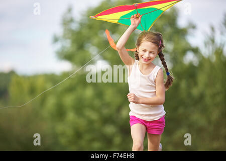 Happy girl flying a kite in summer and having fun Stock Photo