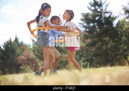 Interracial group of children playing with hula hoop at the park Stock Photo