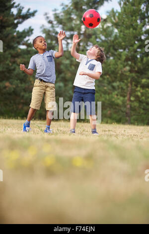 Two boys throwing the ball in the air while playing soccer Stock Photo