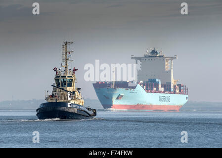 The tug Svitzer Bootle escorts the container ship, Maersk Lota as she steams upriver on the River Thames. Stock Photo
