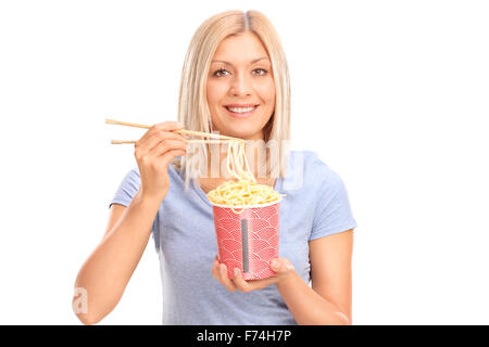Cheerful young woman eating noodles with Chinese sticks and looking at the camera isolated on white background Stock Photo