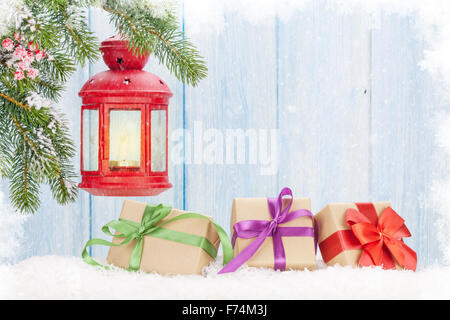 Christmas candle lantern, gift boxes and fir tree in snow. View with copy space Stock Photo