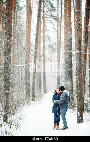 Young Couple Embracing in Winter Forest. Winter Vacations. Weekend Getaway. Space for Text. Natural Colors, Selective Focus. Stock Photo