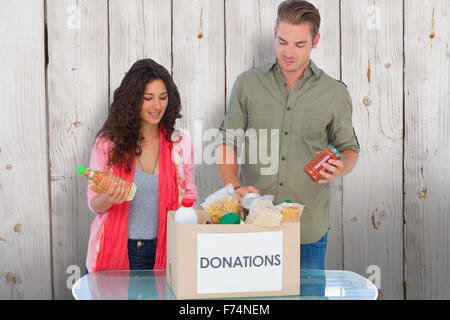 Composite image of volunteers taking out food from donations box Stock Photo
