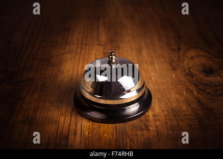 Hotel service call bell on wooden reception front desk, retro toned image. Stock Photo