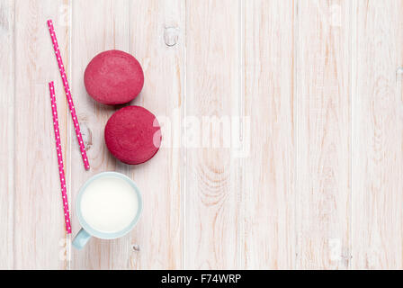 Colorful macarons and cup of milk on white wooden table with copy space Stock Photo