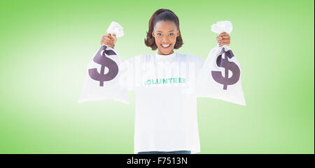 Composite image of smiling volunteer woman holding money bags Stock Photo