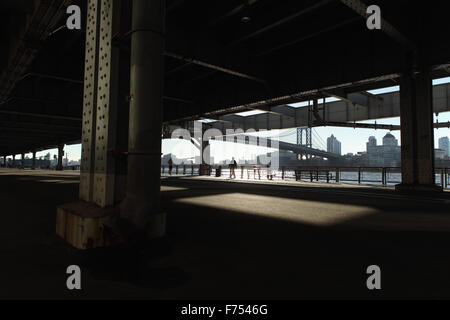 A man runs,  another man walks along the East River Esplanade overpass, New York Stock Photo