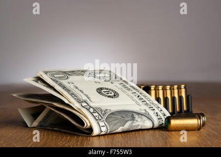 Image of dollar bills with pistols cartridges on a table Stock Photo